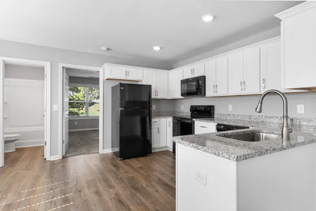 a kitchen with granite countertop a refrigerator and a stove top oven