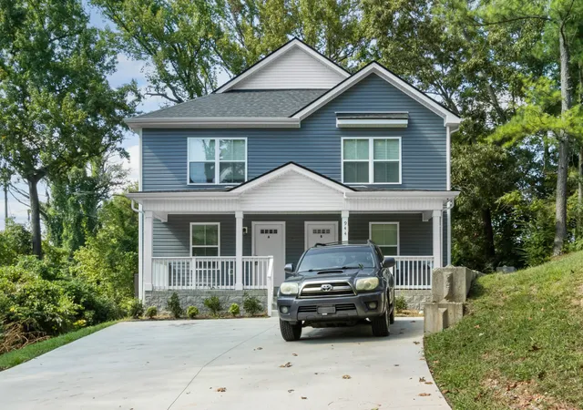 a front view of a house with a garden and trees