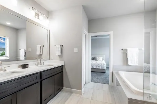 a en suite bathroom with a bathtub double sink and mirror