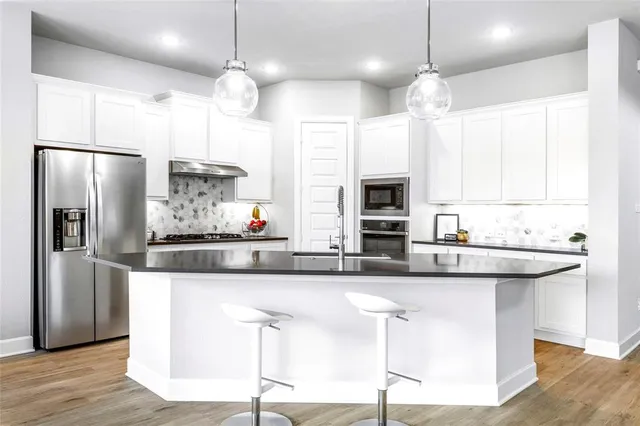 a kitchen with stainless steel appliances granite countertop a sink a stove and a refrigerator