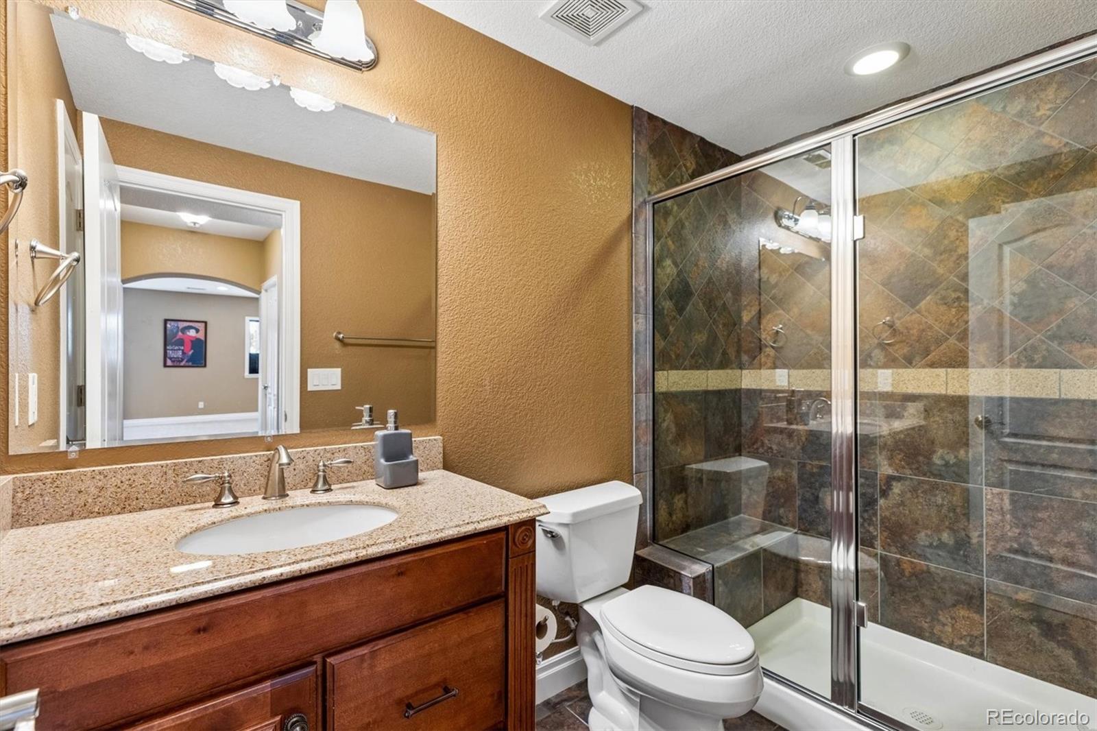 11025 Grayledge Circle Highlands Ranch, CO 80130 - Photo 33 of 46 a bathroom with a granite countertop sink toilet a mirror and shower