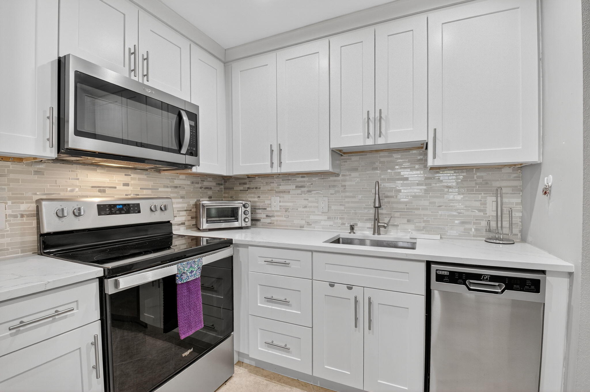 499 Monaco Way, Unit K Delray Beach, FL 33446 - Photo 3 of 33 a kitchen with white cabinets and black appliances