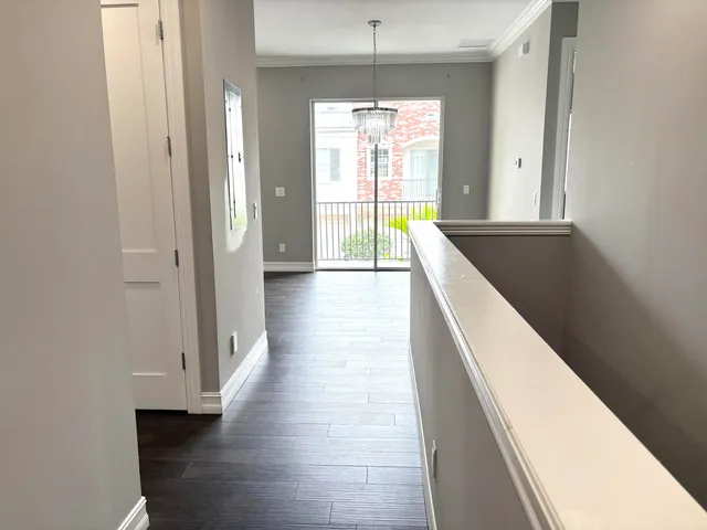 a view of a hallway with wooden floor and a kitchen