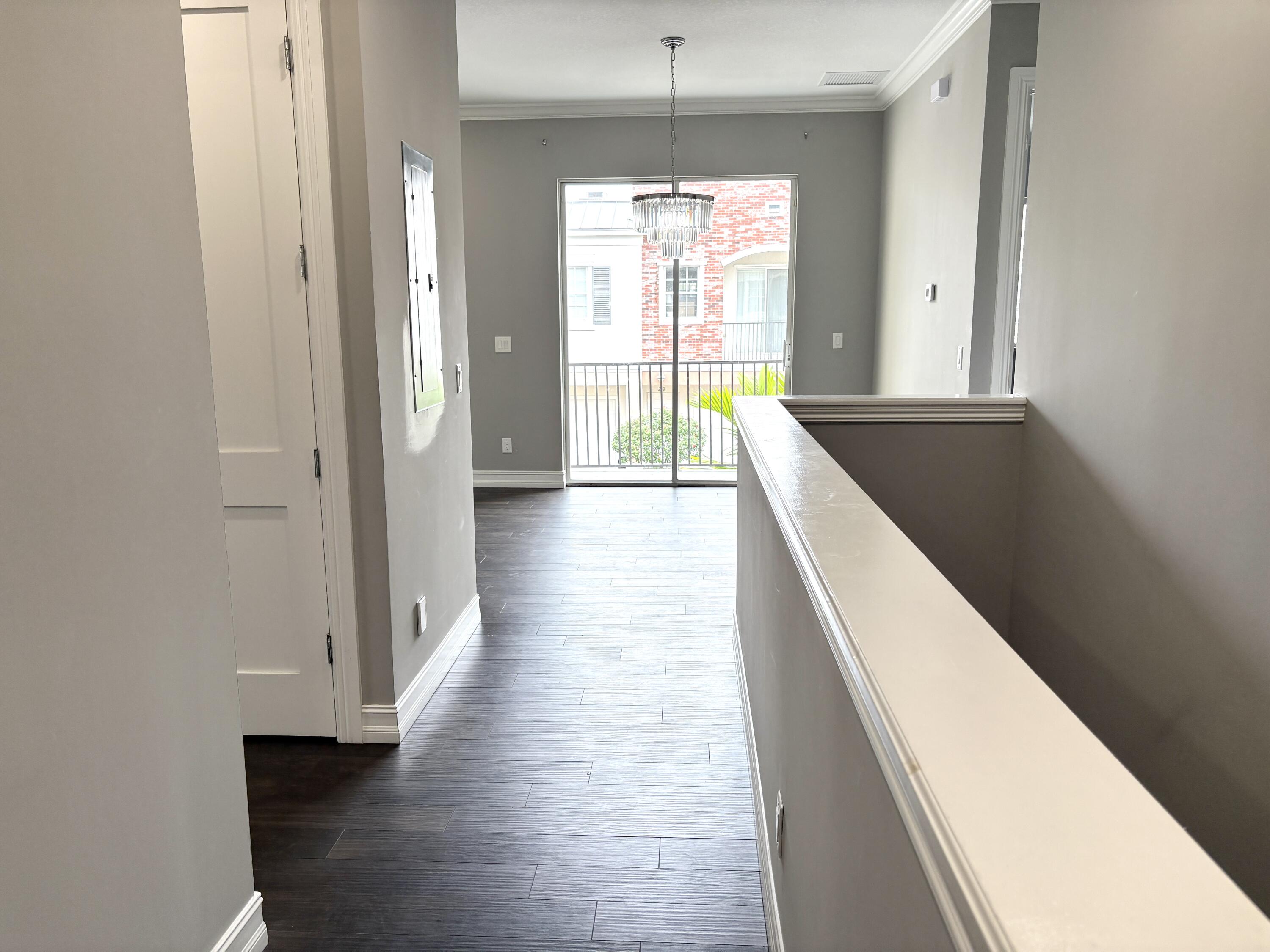 10560 Southwest Stephanie Way, Unit 1202 Port St. Lucie, FL 34987 - Photo 9 of 19 a view of a hallway with wooden floor and a kitchen