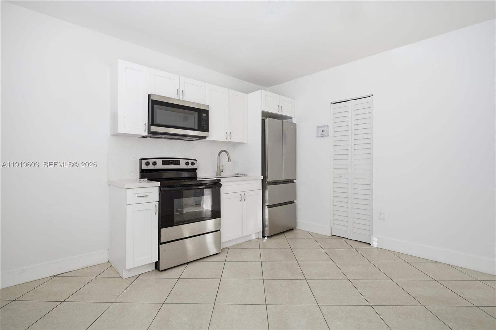 2445 Southwest 18th Street, Unit 3 Miami, FL 33145 - Photo 10 of 18 a kitchen with white cabinets and stainless steel appliances