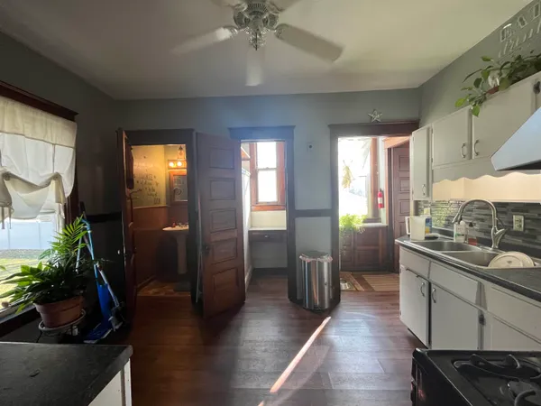 a kitchen with stainless steel appliances kitchen island granite countertop a refrigerator a stove and a sink with wooden floor