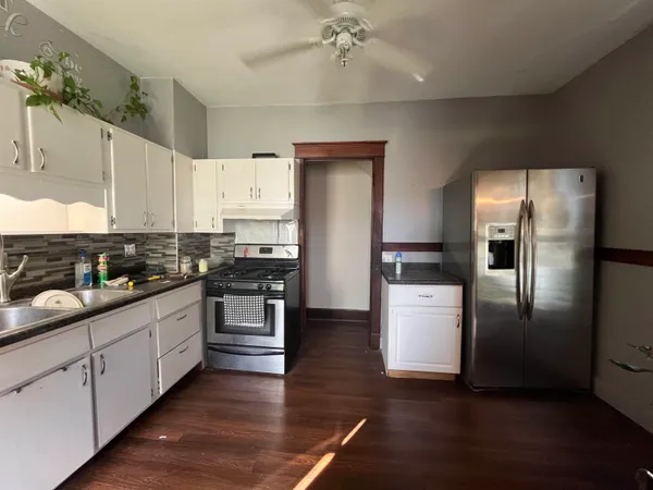 a kitchen with stainless steel appliances white cabinets and wooden floor