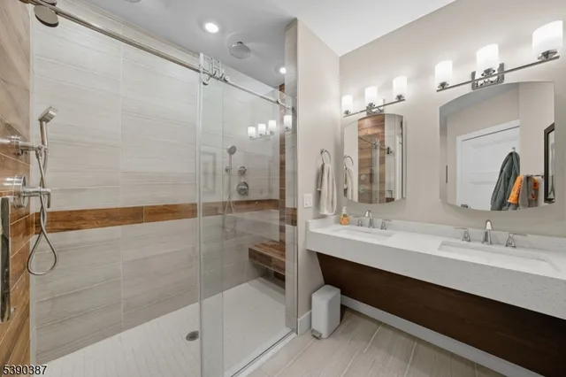 a bathroom with a double vanity sink a toilet a mirror and shower