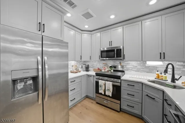 a kitchen with stainless steel appliances granite countertop a refrigerator a stove a sink and white cabinets