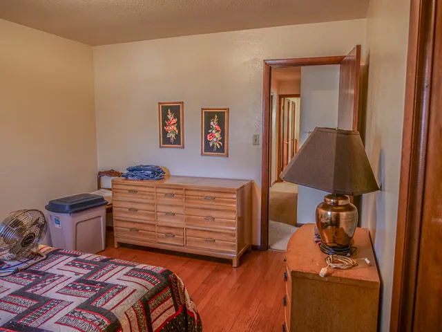 a bedroom with a bed and a lamp on dresser