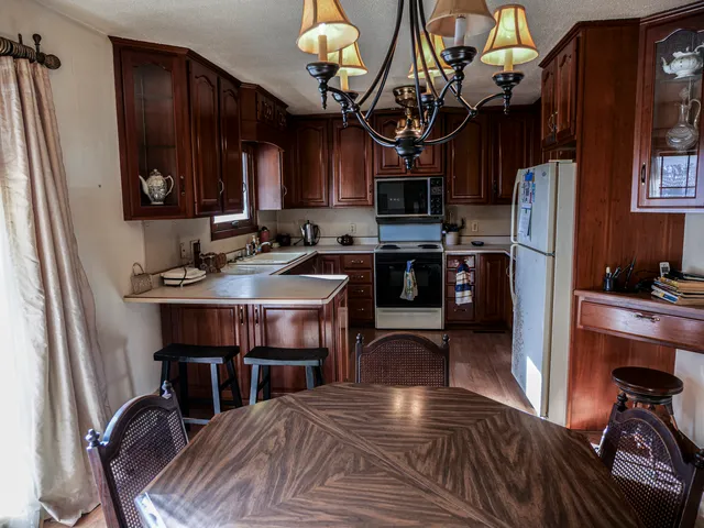 a kitchen with stainless steel appliances granite countertop a sink a stove a refrigerator cabinets and chairs