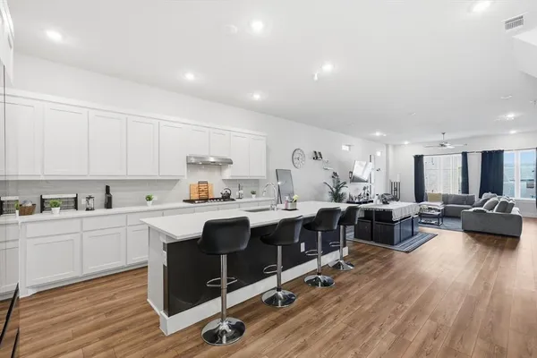 a view of living room with kitchen island stainless steel appliances furniture cabinets and wooden floor