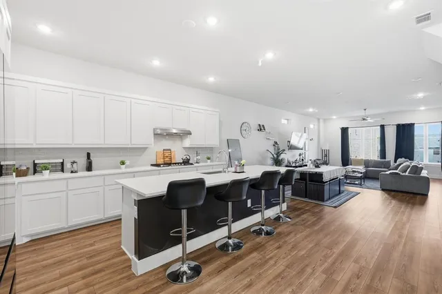 a view of living room with kitchen island stainless steel appliances furniture cabinets and wooden floor