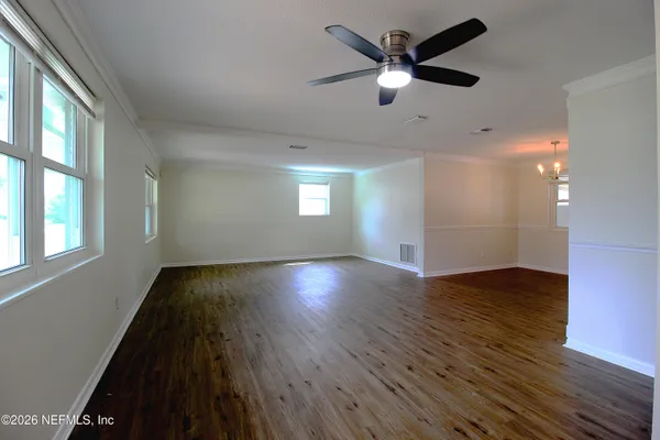 an empty room with wooden floor and windows