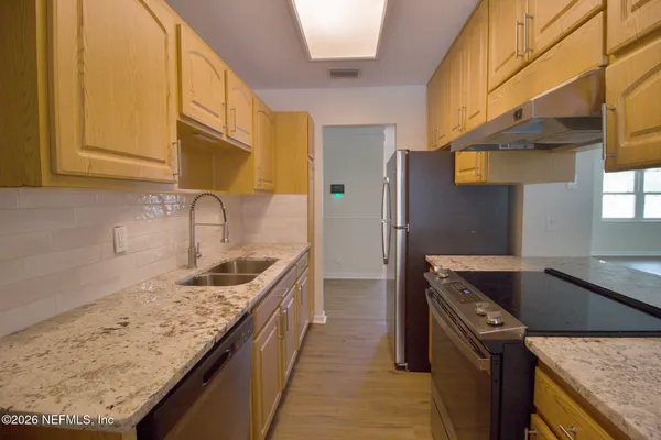 a kitchen with stainless steel appliances granite countertop a sink and a refrigerator
