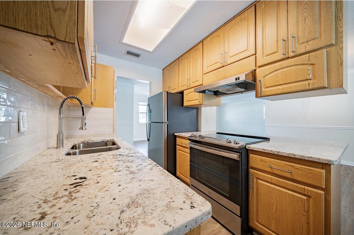7762 Knoll Drive South Jacksonville, FL 32221 - Photo 10 of 22 a kitchen with stainless steel appliances granite countertop a stove and a refrigerator
