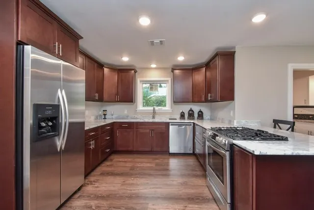 a kitchen with stainless steel appliances granite countertop a refrigerator a sink dishwasher a stove and a refrigerator