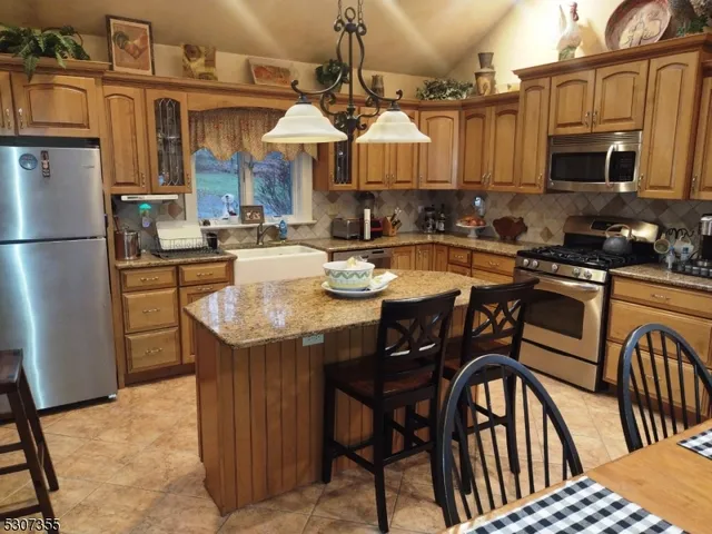 a kitchen with stainless steel appliances granite countertop a stove a sink a dining table and chairs