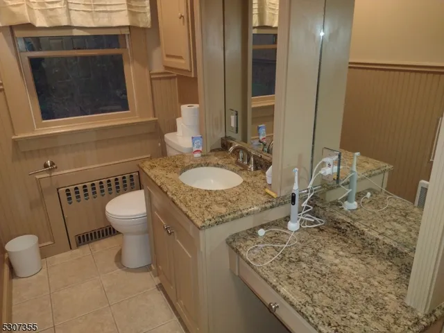 a bathroom with a granite countertop sink a toilet and a mirror