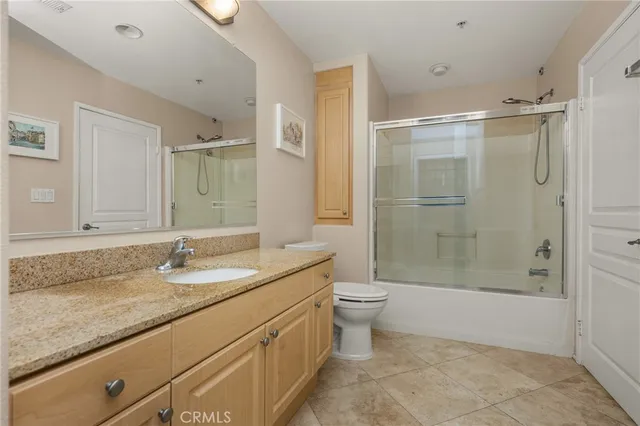 a bathroom with a granite countertop sink a toilet and shower