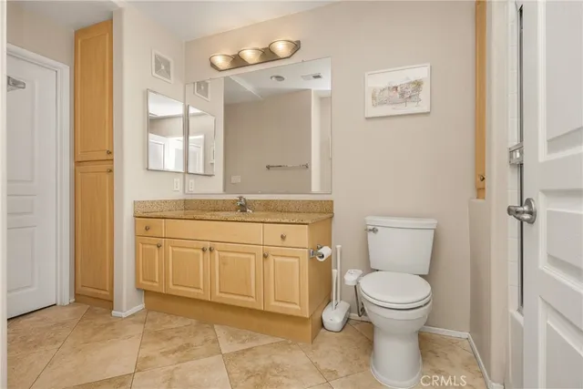 a bathroom with a granite countertop toilet sink and mirror