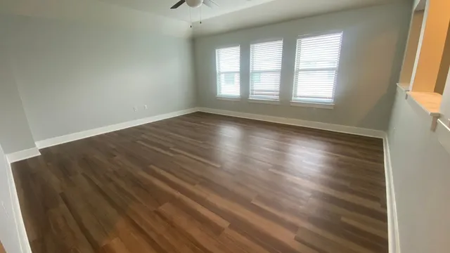 an empty room with wooden floor and windows