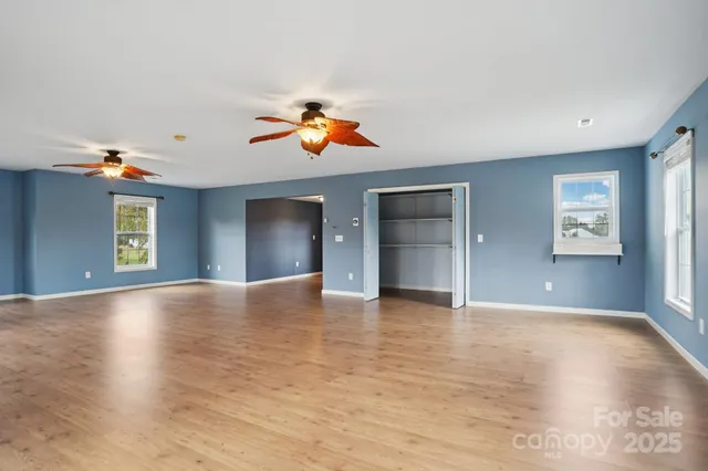 a view of an empty room with window and wooden floor