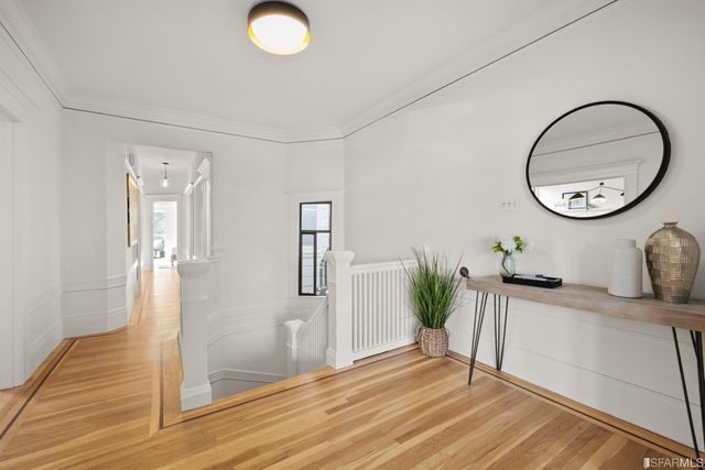 a view of a hallway with wooden floor and a chandelier