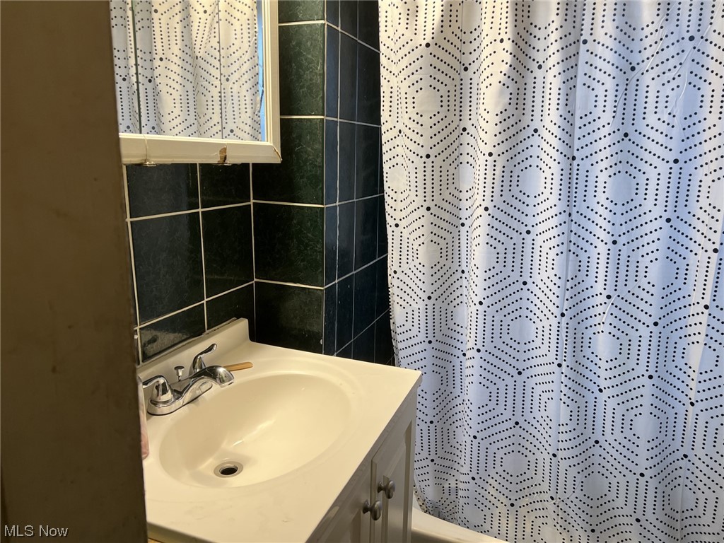 976 Nathaniel Road Cleveland, OH 44110 - Photo 12 of 15 Bathroom featuring tile walls and vanity with extensive cabinet space