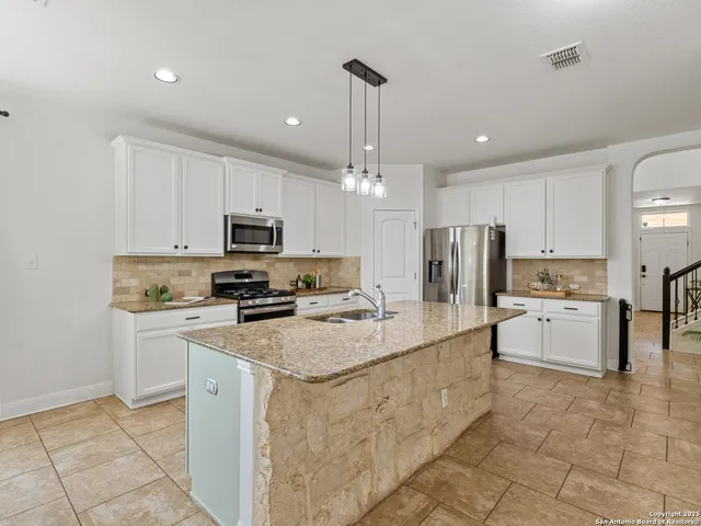 a large kitchen with kitchen island a white counter top space appliances and cabinets