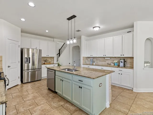 a kitchen with stainless steel appliances granite countertop a sink a stove a refrigerator and island