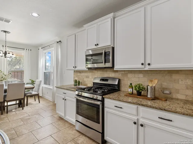a kitchen with granite countertop white cabinets and appliances