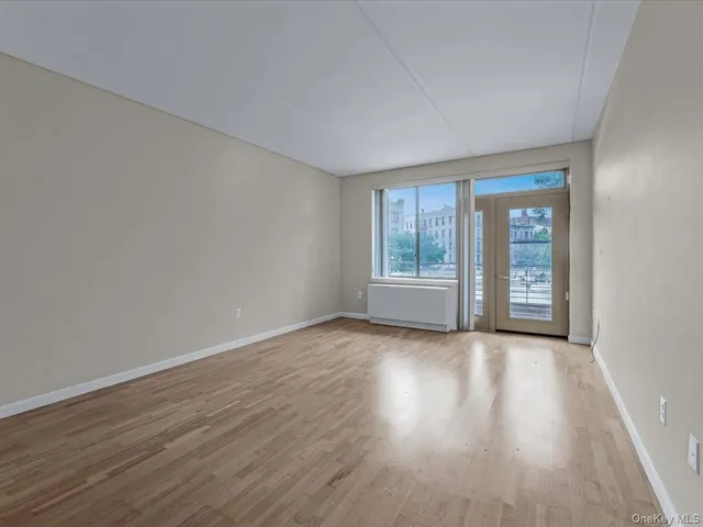 a view of an empty room with wooden floor and fan