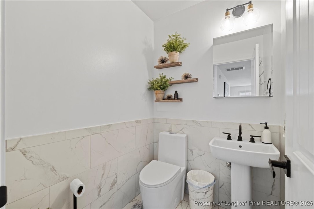 681 New Castle Lane Spring Lake, NC 28390 - Photo 12 of 50 a white toilet sitting next to a bathroom sink