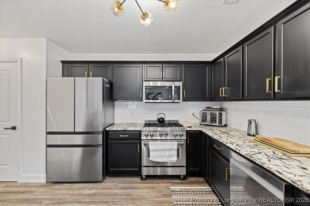 681 New Castle Lane Spring Lake, NC 28390 - Photo 14 of 50 a kitchen with stainless steel appliances granite countertop a refrigerator stove a sink dishwasher and wooden cabinets with wooden floor
