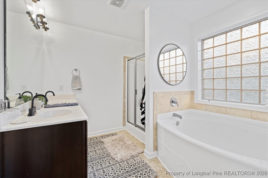 681 New Castle Lane Spring Lake, NC 28390 - Photo 30 of 50 a bathroom with a bathtub a sink a vanity and a window
