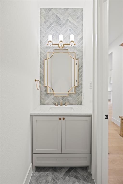 108 Bel Grand Road Haslet, TX 76052 - Photo 12 of 36 Herringbone tile accent wall with a gold-framed mirror and three-light vanity fixture
