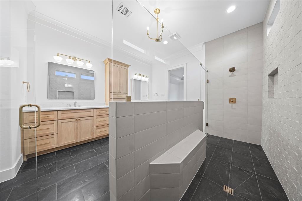 108 Bel Grand Road Haslet, TX 76052 - Photo 32 of 36 Spacious bathroom featuring a glass-enclosed shower with a built-in bench, dual vanity with natural wood-tone cabinetry, white countertop, and dark slate-style floor tiling