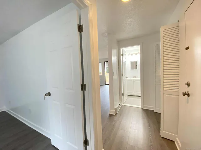 a view of a hallway with wooden floor and closet area