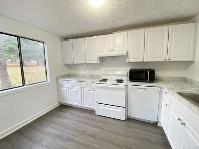 a kitchen with granite countertop white cabinets and white appliances