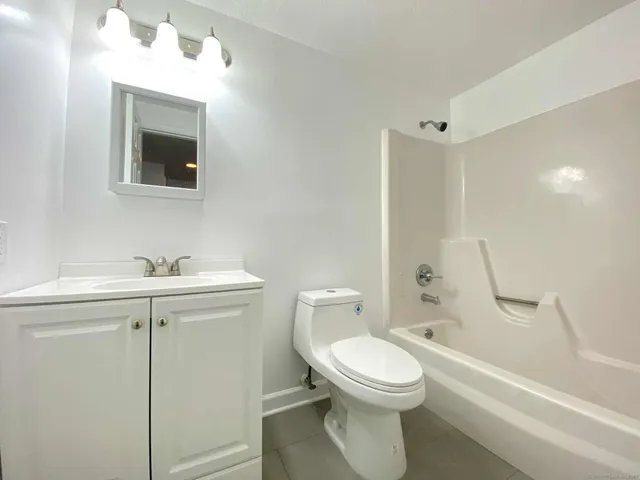a bathroom with a toilet a sink a mirror and bathtub