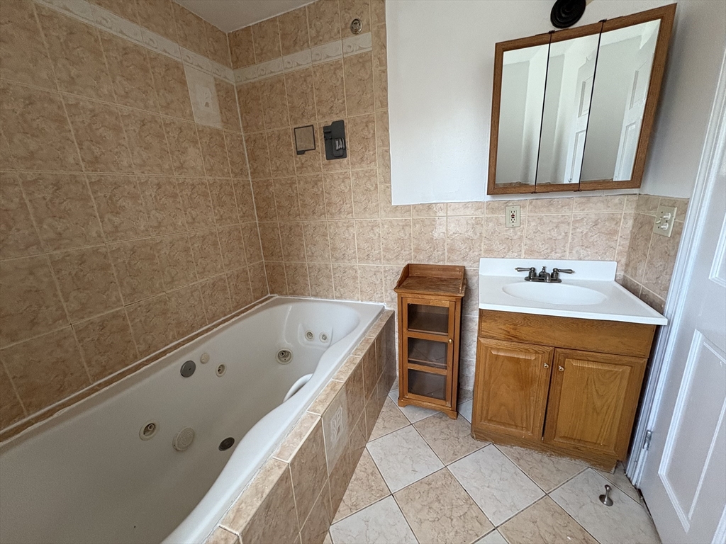 21 Juniper Street, Unit 2 Boston, MA 02119 - Photo 12 of 12 a bathroom with a tub sink and mirror
