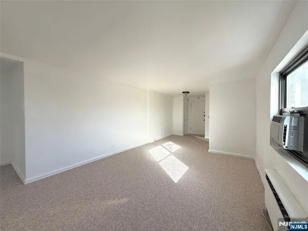 a view of an empty room with a window and a kitchen
