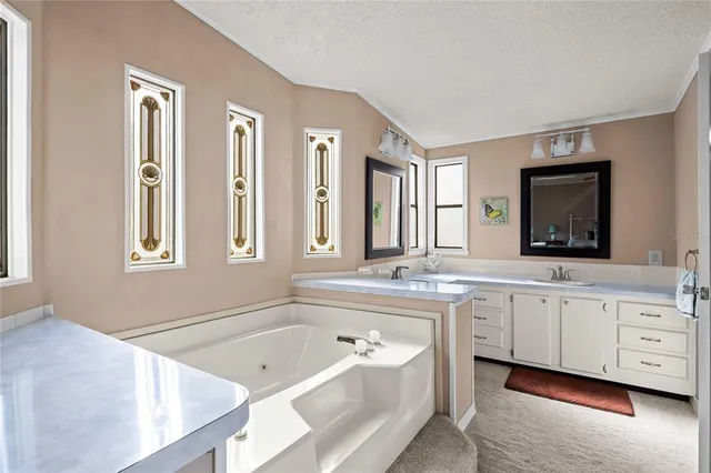 a bathroom with a tub a double vanity sink a window and a mirror