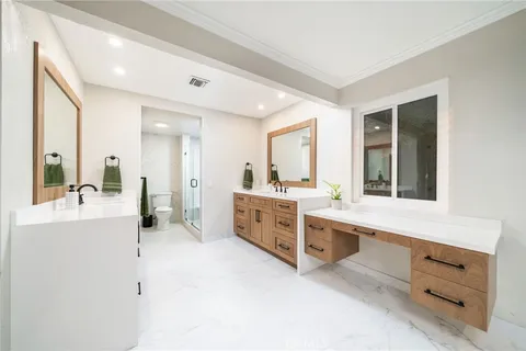 a large white bathroom with a double vanity sink a mirror and a bathtub
