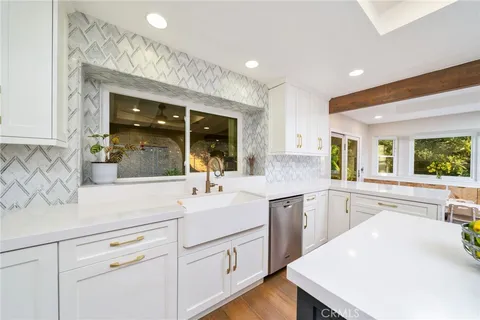 a kitchen with sink a mirror and cabinets