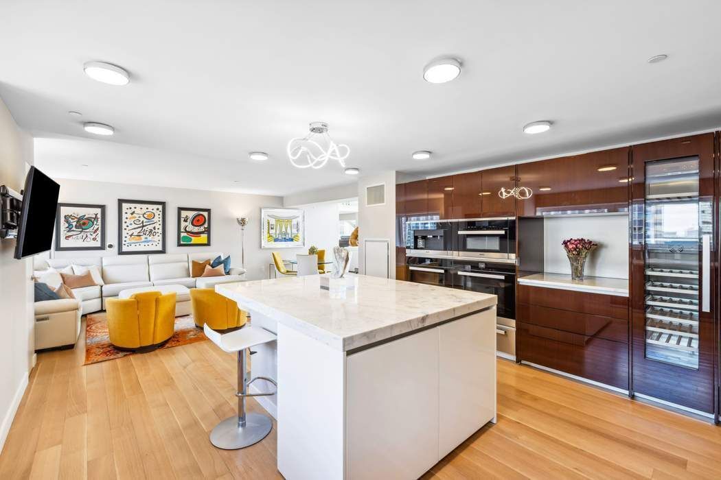 135 West 52nd Street, Unit PH1 Manhattan, NY 10019 - Photo 4 of 29 a kitchen with stainless steel appliances granite countertop a sink dishwasher stove and oven with wooden floor