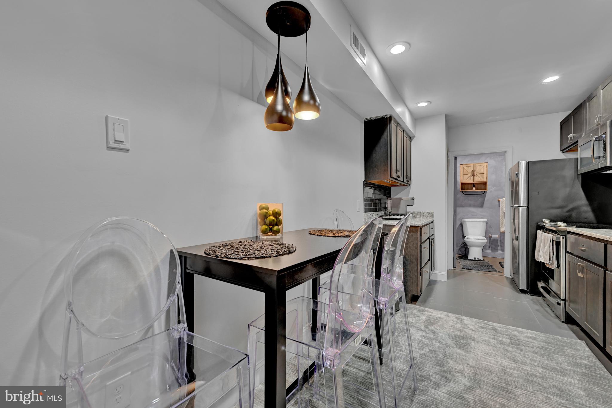 1709 Bank Street Baltimore, MD 21231 - Photo 32 of 49 a kitchen with stainless steel appliances kitchen island granite countertop a table chairs in it and wooden floors