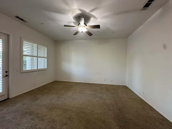 an empty room with windows and chandelier fan
