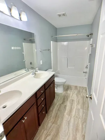 a spacious bathroom with a double vanity sink toilet mirror and shower